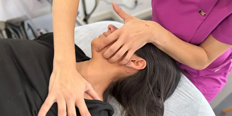 Las manos de Mónica Gómez en el cuello y la mandíbula de una paciente