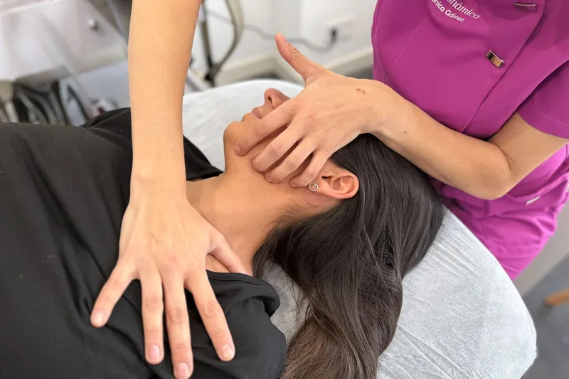 Las manos de Mónica Gómez en el cuello y la mandíbula de una paciente tumbada